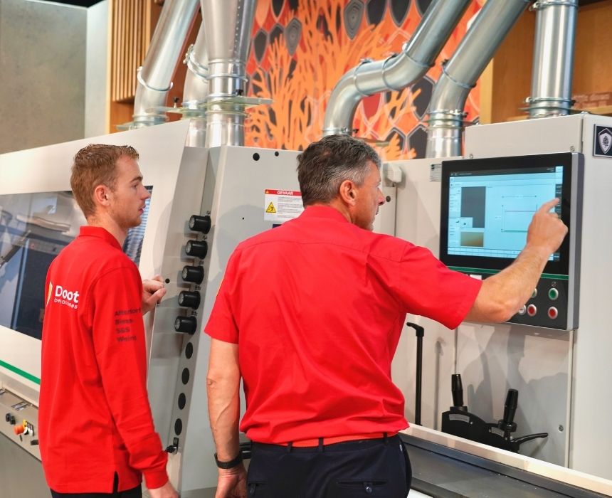 Collega kijkt met andere collega mee bij cnc-machine in showroom