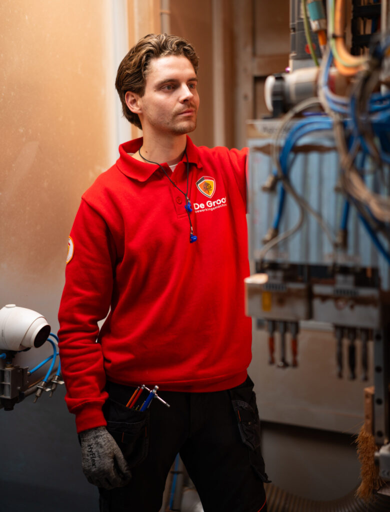 Servicetechnicus werkt aan een cnc-machine bij een klant op locatie.
